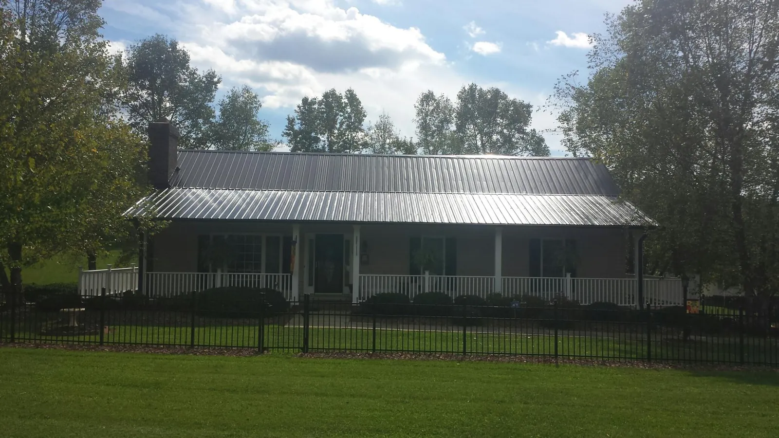Gray metal roof on a brick ranch with a full width front porch — Gutter Guard Installation work by our crew in De Pere