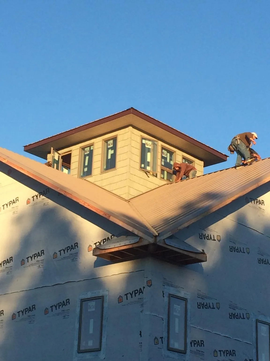 Roofers working around a rooftop cupola on a new metal roof at sunset — Roof Waterproofing in De Pere by Roofing Brothers